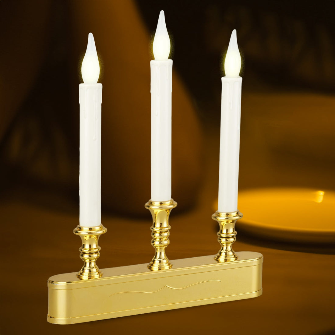Candlestick, gold base with three white LED taper candles against warm dark background