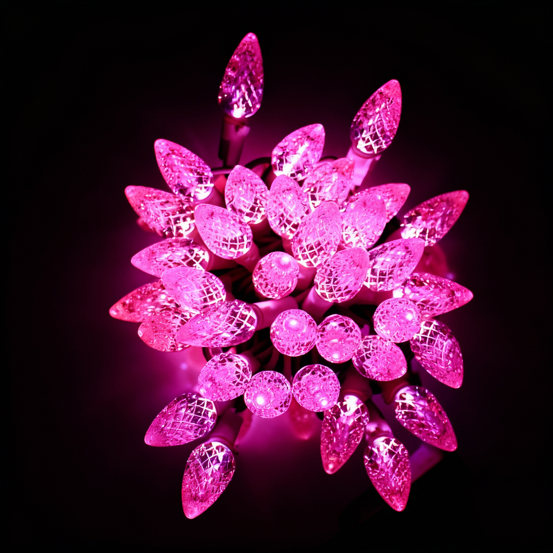 String lights, pink faceted cone bulbs, bundled cluster against dark background
