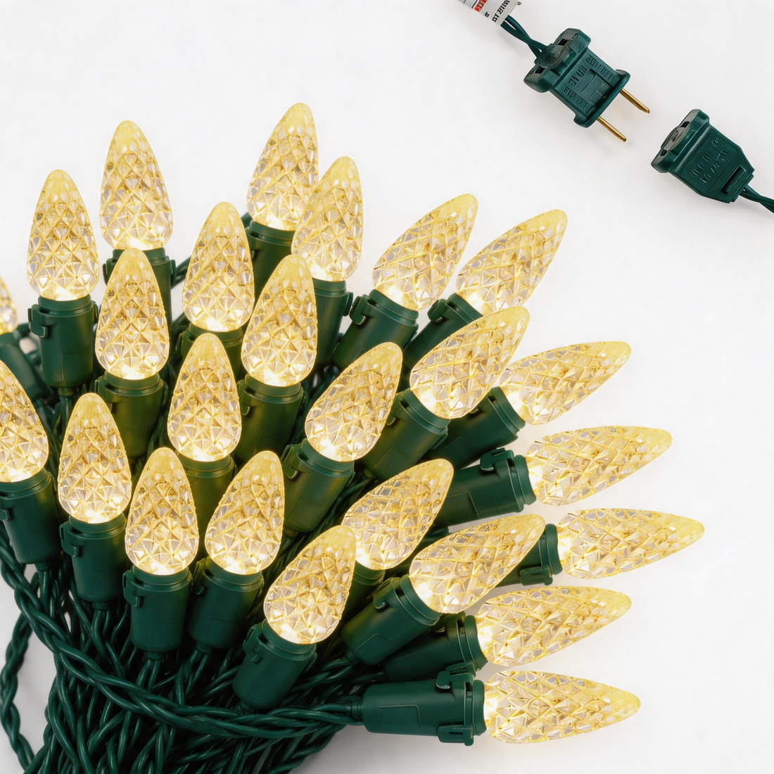 String lights, green cord, faceted cone clear bulbs, bundled on white background with plug connectors